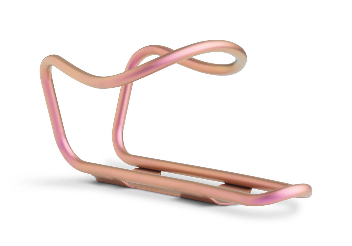 A minimalist, curved titanium bicycle water bottle cage in a pink finish, shown on a clean white background with a soft shadow.