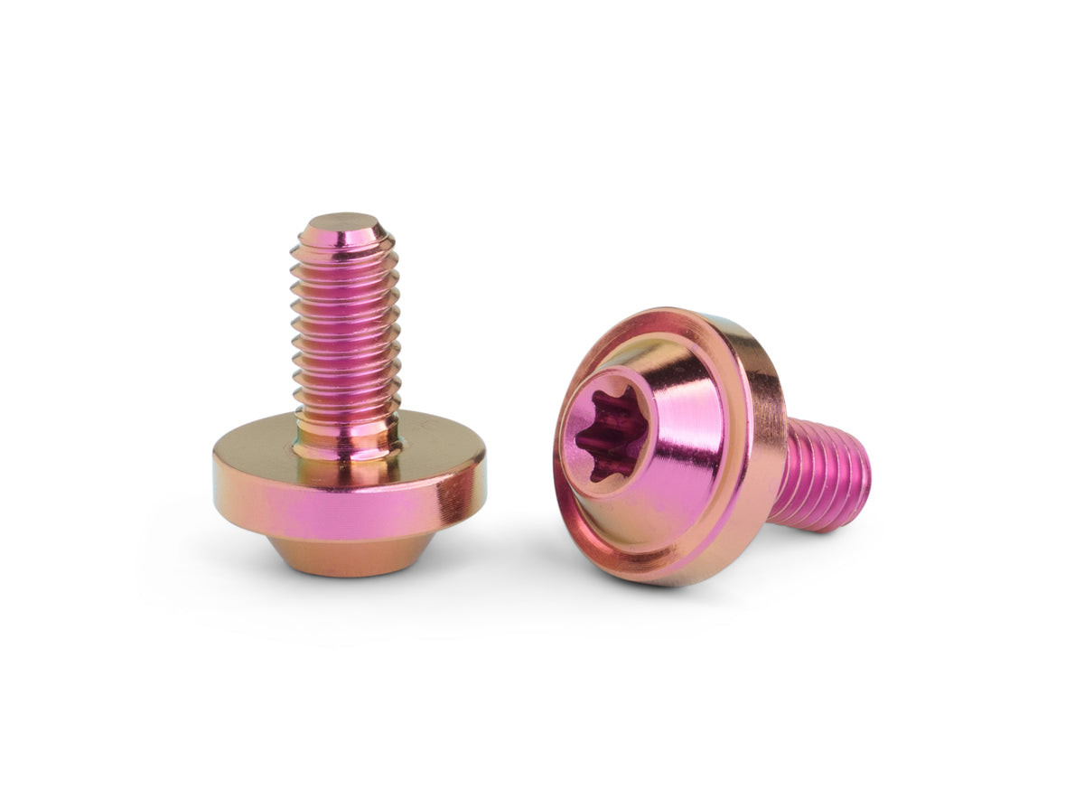 Two metallic pink and copper-colored flat head screws with star drive sockets, shown on a clean white background.