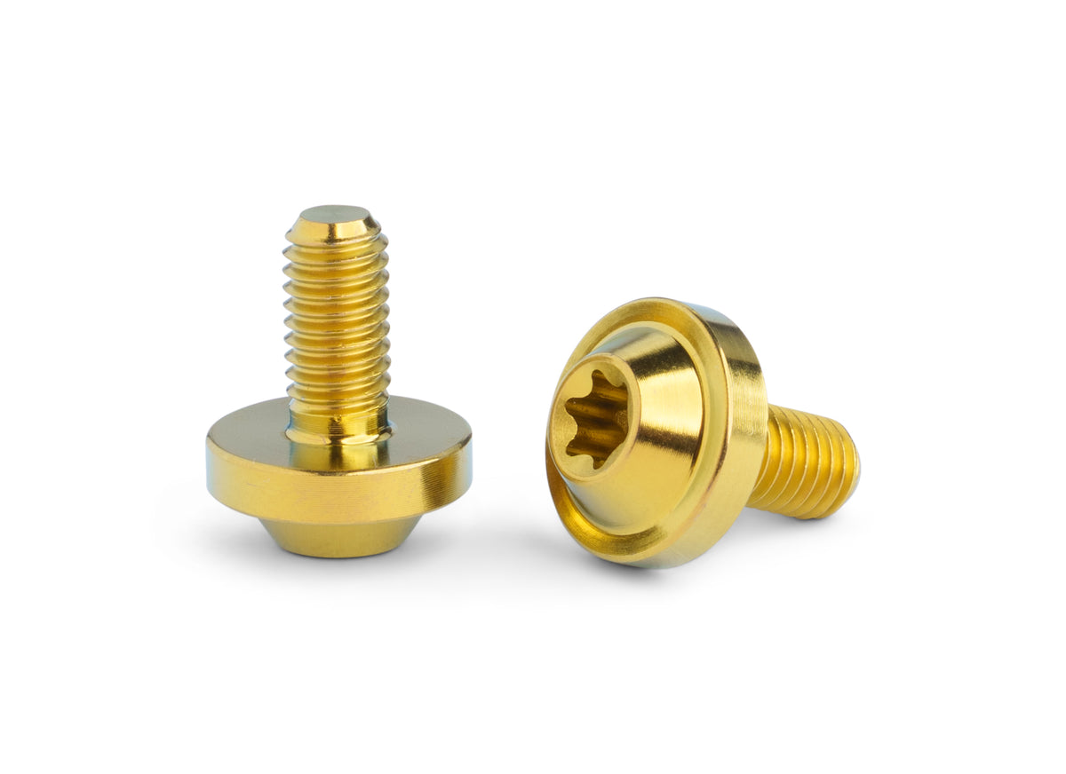 Two yellow-colored titanium screws with a star drive head, shown from different angles on a clean white background.